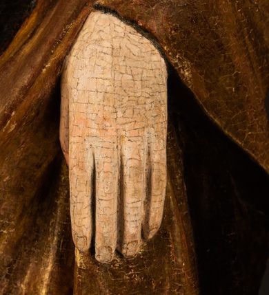 Zdjęcie nr 17: Przyścienna rzeźba Madonny z Dzieciątkiem jest z tyłu wydrążona. W tyle głowy Marii wbity jest hak służący do umocowania w ołtarzu. Matka Boska w całej postaci została ukazana w lekkim kontrapoście z charakterystycznym przegięciem w kształcie odwróconej litery &quot;S&quot;. Na prawej ręce trzyma Dzieciątko Jezus, lewą zaś ręką opuszczoną wzdłuż tułowia podtrzymuje nadgarstkiem fałdy płaszcza. Madonna ma pociągłą, zamyśloną twarz o jasnej karnacji, wysokie czoło i pucułowate, rumiane policzki. Ma prosty nos, migdałowe oczy oraz wydatne usta i podbródek. Jej głowę osadzoną na długiej szyi okalają zaczesane do tyłu brązowe włosy, widoczne spod osuwającej się chusty opadającej na ramiona dwoma festonami. Maria ubrana jest w złoconą suknię laserowaną ciepłą czerwienią oraz złocony płaszcz podbity srebrną podszewką z oliwkowo zielonym laserunkiem. Z przodu płaszcz drapowany jest w łukowate fałdy. Jedna z nich biegnie diagonalnie od prawej dłoni ku lewej stopie Madonny. Płaszcz po bokach postaci spływa rurkowatymi kaskadami. Maria na głowię ma wysoką, złotą koronę ze sterczynami o trójlistnych zakończeniach. Mały Jezus został ujęty w trzech czwartych z nieznacznie odchyloną głową do tyłu i skrzyżowanymi nóżkami. Lewą rękę kładzie na piersi matki, w prawej zaś trzyma złocone jabłko. Ma okrągłą, pucułowatą twarz o rumianych policzkach. Charakteryzuje ją prosty nosek, wydatne wargi i podbródek oraz wyraziste, szeroko otwarte oczy. Jego głowę z wysokim czołem okalają krótkie brązowe włosy. Ubrany jest w złocistą długą tunikę odsłaniającą fragmenty stóp.   