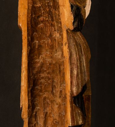 Zdjęcie nr 23: Przyścienna rzeźba Madonny z Dzieciątkiem jest z tyłu wydrążona. W tyle głowy Marii wbity jest hak służący do umocowania w ołtarzu. Matka Boska w całej postaci została ukazana w lekkim kontrapoście z charakterystycznym przegięciem w kształcie odwróconej litery "S". Na prawej ręce trzyma Dzieciątko Jezus, lewą zaś ręką opuszczoną wzdłuż tułowia podtrzymuje nadgarstkiem fałdy płaszcza. Madonna ma pociągłą, zamyśloną twarz o jasnej karnacji, wysokie czoło i pucułowate, rumiane policzki. Ma prosty nos, migdałowe oczy oraz wydatne usta i podbródek. Jej głowę osadzoną na długiej szyi okalają zaczesane do tyłu brązowe włosy, widoczne spod osuwającej się chusty opadającej na ramiona dwoma festonami. Maria ubrana jest w złoconą suknię laserowaną ciepłą czerwienią oraz złocony płaszcz podbity srebrną podszewką z oliwkowo zielonym laserunkiem. Z przodu płaszcz drapowany jest w łukowate fałdy. Jedna z nich biegnie diagonalnie od prawej dłoni ku lewej stopie Madonny. Płaszcz po bokach postaci spływa rurkowatymi kaskadami. Maria na głowię ma wysoką, złotą koronę ze sterczynami o trójlistnych zakończeniach. Mały Jezus został ujęty w trzech czwartych z nieznacznie odchyloną głową do tyłu i skrzyżowanymi nóżkami. Lewą rękę kładzie na piersi matki, w prawej zaś trzyma złocone jabłko. Ma okrągłą, pucułowatą twarz o rumianych policzkach. Charakteryzuje ją prosty nosek, wydatne wargi i podbródek oraz wyraziste, szeroko otwarte oczy. Jego głowę z wysokim czołem okalają krótkie brązowe włosy. Ubrany jest w złocistą długą tunikę odsłaniającą fragmenty stóp.   