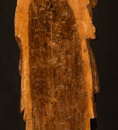 Zdjęcie nr 24: Przyścienna rzeźba Madonny z Dzieciątkiem jest z tyłu wydrążona. W tyle głowy Marii wbity jest hak służący do umocowania w ołtarzu. Matka Boska w całej postaci została ukazana w lekkim kontrapoście z charakterystycznym przegięciem w kształcie odwróconej litery "S". Na prawej ręce trzyma Dzieciątko Jezus, lewą zaś ręką opuszczoną wzdłuż tułowia podtrzymuje nadgarstkiem fałdy płaszcza. Madonna ma pociągłą, zamyśloną twarz o jasnej karnacji, wysokie czoło i pucułowate, rumiane policzki. Ma prosty nos, migdałowe oczy oraz wydatne usta i podbródek. Jej głowę osadzoną na długiej szyi okalają zaczesane do tyłu brązowe włosy, widoczne spod osuwającej się chusty opadającej na ramiona dwoma festonami. Maria ubrana jest w złoconą suknię laserowaną ciepłą czerwienią oraz złocony płaszcz podbity srebrną podszewką z oliwkowo zielonym laserunkiem. Z przodu płaszcz drapowany jest w łukowate fałdy. Jedna z nich biegnie diagonalnie od prawej dłoni ku lewej stopie Madonny. Płaszcz po bokach postaci spływa rurkowatymi kaskadami. Maria na głowię ma wysoką, złotą koronę ze sterczynami o trójlistnych zakończeniach. Mały Jezus został ujęty w trzech czwartych z nieznacznie odchyloną głową do tyłu i skrzyżowanymi nóżkami. Lewą rękę kładzie na piersi matki, w prawej zaś trzyma złocone jabłko. Ma okrągłą, pucułowatą twarz o rumianych policzkach. Charakteryzuje ją prosty nosek, wydatne wargi i podbródek oraz wyraziste, szeroko otwarte oczy. Jego głowę z wysokim czołem okalają krótkie brązowe włosy. Ubrany jest w złocistą długą tunikę odsłaniającą fragmenty stóp.   