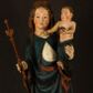 Zdjęcie nr 1: Rzeźba drążona, ukazująca Matkę Boską z Dzieciątkiem. Maria ustawiona frontalnie, w delikatnym kontrapoście, na lewym ręku trzyma Dzieciątko, w prawym dzierży berło. Twarz okrągła z wysokim czołem, drobnymi ustami i małymi oczami o delikatnie zarysowanych łukach brwiowych. Włosy jasne, ułożone w skręcone pukle spływające na plecy. Maria ubrana jest w białą suknię zdobioną drobnymi, niebieskimi gwiazdkami, ciemnobłękitny płaszcz z bordową podszewką spięty na piersi oraz spiczaste, brązowe buty. Na głowie ma założony ciemnoniebieski welon z bordową podszewką, spływający na ramiona i piersi oraz brązową podstawę do niezachowanej korony. Draperia szat miękka o wyraźnie zaznaczonych, licznych fałdach misowych i kaskadowych. Dzieciątko ukazane w pozycji siedzącej, zwrócone w prawo. W lewej dłoni trzyma jabłko królewskie, a prawą wyprostowaną podnosi na wysokość tułowia. Twarz pełna o dziecięcych rysach z małymi ustami, okolona krótkimi i kędzierzawymi włosami. Polichromia w odsłoniętych partiach ciała naturalistyczna, berło polichromowane na brązowo.