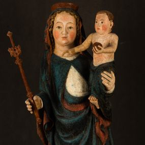 Zdjęcie nr 1: Rzeźba drążona, ukazująca Matkę Boską z Dzieciątkiem. Maria ustawiona frontalnie, w delikatnym kontrapoście, na lewym ręku trzyma Dzieciątko, w prawym dzierży berło. Twarz okrągła z wysokim czołem, drobnymi ustami i małymi oczami o delikatnie zarysowanych łukach brwiowych. Włosy jasne, ułożone w skręcone pukle spływające na plecy. Maria ubrana jest w białą suknię zdobioną drobnymi, niebieskimi gwiazdkami, ciemnobłękitny płaszcz z bordową podszewką spięty na piersi oraz spiczaste, brązowe buty. Na głowie ma założony ciemnoniebieski welon z bordową podszewką, spływający na ramiona i piersi oraz brązową podstawę do niezachowanej korony. Draperia szat miękka o wyraźnie zaznaczonych, licznych fałdach misowych i kaskadowych. Dzieciątko ukazane w pozycji siedzącej, zwrócone w prawo. W lewej dłoni trzyma jabłko królewskie, a prawą wyprostowaną podnosi na wysokość tułowia. Twarz pełna o dziecięcych rysach z małymi ustami, okolona krótkimi i kędzierzawymi włosami. Polichromia w odsłoniętych partiach ciała naturalistyczna, berło polichromowane na brązowo.