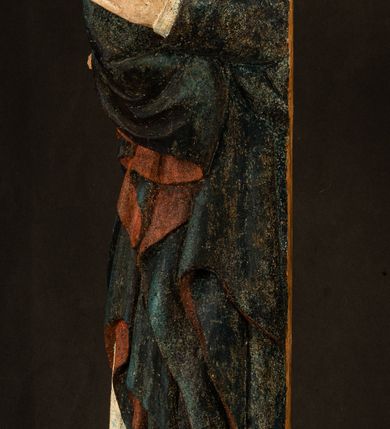 Zdjęcie nr 19: Rzeźba drążona, ukazująca Matkę Boską z Dzieciątkiem. Maria ustawiona frontalnie, w delikatnym kontrapoście, na lewym ręku trzyma Dzieciątko, w prawym dzierży berło. Twarz okrągła z wysokim czołem, drobnymi ustami i małymi oczami o delikatnie zarysowanych łukach brwiowych. Włosy jasne, ułożone w skręcone pukle spływające na plecy. Maria ubrana jest w białą suknię zdobioną drobnymi, niebieskimi gwiazdkami, ciemnobłękitny płaszcz z bordową podszewką spięty na piersi oraz spiczaste, brązowe buty. Na głowie ma założony ciemnoniebieski welon z bordową podszewką, spływający na ramiona i piersi oraz brązową podstawę do niezachowanej korony. Draperia szat miękka o wyraźnie zaznaczonych, licznych fałdach misowych i kaskadowych. Dzieciątko ukazane w pozycji siedzącej, zwrócone w prawo. W lewej dłoni trzyma jabłko królewskie, a prawą wyprostowaną podnosi na wysokość tułowia. Twarz pełna o dziecięcych rysach z małymi ustami, okolona krótkimi i kędzierzawymi włosami. Polichromia w odsłoniętych partiach ciała naturalistyczna, berło polichromowane na brązowo.