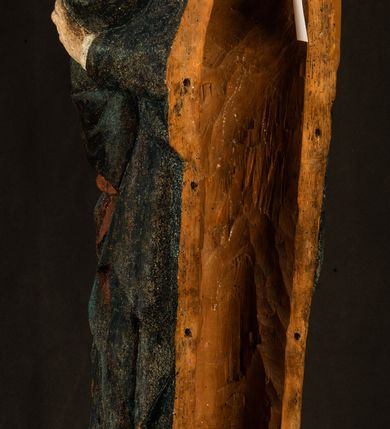 Zdjęcie nr 21: Rzeźba drążona, ukazująca Matkę Boską z Dzieciątkiem. Maria ustawiona frontalnie, w delikatnym kontrapoście, na lewym ręku trzyma Dzieciątko, w prawym dzierży berło. Twarz okrągła z wysokim czołem, drobnymi ustami i małymi oczami o delikatnie zarysowanych łukach brwiowych. Włosy jasne, ułożone w skręcone pukle spływające na plecy. Maria ubrana jest w białą suknię zdobioną drobnymi, niebieskimi gwiazdkami, ciemnobłękitny płaszcz z bordową podszewką spięty na piersi oraz spiczaste, brązowe buty. Na głowie ma założony ciemnoniebieski welon z bordową podszewką, spływający na ramiona i piersi oraz brązową podstawę do niezachowanej korony. Draperia szat miękka o wyraźnie zaznaczonych, licznych fałdach misowych i kaskadowych. Dzieciątko ukazane w pozycji siedzącej, zwrócone w prawo. W lewej dłoni trzyma jabłko królewskie, a prawą wyprostowaną podnosi na wysokość tułowia. Twarz pełna o dziecięcych rysach z małymi ustami, okolona krótkimi i kędzierzawymi włosami. Polichromia w odsłoniętych partiach ciała naturalistyczna, berło polichromowane na brązowo.