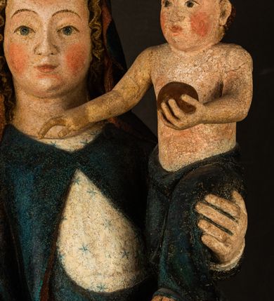 Zdjęcie nr 9: Rzeźba drążona, ukazująca Matkę Boską z Dzieciątkiem. Maria ustawiona frontalnie, w delikatnym kontrapoście, na lewym ręku trzyma Dzieciątko, w prawym dzierży berło. Twarz okrągła z wysokim czołem, drobnymi ustami i małymi oczami o delikatnie zarysowanych łukach brwiowych. Włosy jasne, ułożone w skręcone pukle spływające na plecy. Maria ubrana jest w białą suknię zdobioną drobnymi, niebieskimi gwiazdkami, ciemnobłękitny płaszcz z bordową podszewką spięty na piersi oraz spiczaste, brązowe buty. Na głowie ma założony ciemnoniebieski welon z bordową podszewką, spływający na ramiona i piersi oraz brązową podstawę do niezachowanej korony. Draperia szat miękka o wyraźnie zaznaczonych, licznych fałdach misowych i kaskadowych. Dzieciątko ukazane w pozycji siedzącej, zwrócone w prawo. W lewej dłoni trzyma jabłko królewskie, a prawą wyprostowaną podnosi na wysokość tułowia. Twarz pełna o dziecięcych rysach z małymi ustami, okolona krótkimi i kędzierzawymi włosami. Polichromia w odsłoniętych partiach ciała naturalistyczna, berło polichromowane na brązowo.
