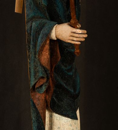 Zdjęcie nr 18: Rzeźba drążona, ukazująca Matkę Boską z Dzieciątkiem. Maria ustawiona frontalnie, w delikatnym kontrapoście, na lewym ręku trzyma Dzieciątko, w prawym dzierży berło. Twarz okrągła z wysokim czołem, drobnymi ustami i małymi oczami o delikatnie zarysowanych łukach brwiowych. Włosy jasne, ułożone w skręcone pukle spływające na plecy. Maria ubrana jest w białą suknię zdobioną drobnymi, niebieskimi gwiazdkami, ciemnobłękitny płaszcz z bordową podszewką spięty na piersi oraz spiczaste, brązowe buty. Na głowie ma założony ciemnoniebieski welon z bordową podszewką, spływający na ramiona i piersi oraz brązową podstawę do niezachowanej korony. Draperia szat miękka o wyraźnie zaznaczonych, licznych fałdach misowych i kaskadowych. Dzieciątko ukazane w pozycji siedzącej, zwrócone w prawo. W lewej dłoni trzyma jabłko królewskie, a prawą wyprostowaną podnosi na wysokość tułowia. Twarz pełna o dziecięcych rysach z małymi ustami, okolona krótkimi i kędzierzawymi włosami. Polichromia w odsłoniętych partiach ciała naturalistyczna, berło polichromowane na brązowo.