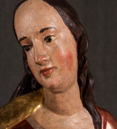 Zdjęcie nr 9: Całopostaciowa, pełnoplastyczna figura Madonny z Dzieciątkiem stojącej w wydatnym kontrapoście na podstawie o wykroju w kształcie półkola z parą wklęsek. Sylwetkę Marii charakteryzuje S-kształtny układ. Zwróconą w trzech czwartych w prawo, lekko przechyloną w bok głowę charakteryzują długie, ciemne, kręcone włosy opadające na plecy i lewe ramię oraz pociągła, owalna twarz o bardzo wysokim czole, łagodnych lukach ciemnych brwi, migdałowatych oczach, długim, zaokrąglonym na końcu nosie, pełnych, zaróżowionych policzkach, kształtnych ustach i zaokrąglonym podbródku. Długą szyję uwydatnia głęboki, półkolisty dekolt długiej, czerwonej sukni ze srebrnymi lamówkami, o długich, wąskich rękawach i ściśle przylegającej do tułowia. Sylwetkę ciasno osłania złocony płaszcz narzucony na prawe ramię osłaniając rękę talię i nogi do wysokości łydek. Spod sukni widoczne są ciemnobrązowe, spiczaste buty. Draperie cechuje dekoracyjny układ fałdowań w postaci spiętrzonej kaskady drobnych fałd rurkowych wzdłuż prawego biodra i nogi Marii oraz 3 promieniście opadających, C-kształtnych załamań. Nieco masywniejsze fałdy w dolnej partii sukni załamują się ostrymi formami pod wpływem styku z obuwiem i podłożem. Pod stopami sierp księżyca.  Maria prawą ręką podtrzymuje siedzące, zwrócone w trzech czwartych w lewo Dzieciątko lewą dłonią ujmując jego stopy. Jego nagą sylwetkę charakteryzuje stosunkowo sumaryczny modelunek ciała. Lekko odchyloną do tyłu głowę charakteryzuje owalna twarz o pełnych, zaokrąglonych rysach, z lekko wypukłym czołem, wyrazistymi łukami ciemnych, opadających brwi, dużymi, ciemnymi oczami, krótkim, lekko zadartym nosem, pełnymi ustami, zaróżowionymi policzkami i wyraźnie zarysowanym podbródkiem. Włosy krótkie, ciemne, mocno skręcone z wyraźnym puklem nad czołem, szyja krótka i szeroka. Zgięte w łokciach ręce uniesione są na wysokości klatki piersiowej, prawa bliżej sylwetki w geście błogosławieństwa, lewa nieco wysunięta do przodu z dłonią odwróconą ku górze. Prawa noga wyprostowana, lewa lekko zgięta w kolanie.       