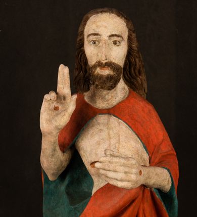 Zdjęcie nr 1: Pełnoplastyczna rzeźba ukazuje frontalnie w całej postaci zmartwychwstałego Chrystusa stojącego w kontrapoście na niewielkim wzgórku. Jego prawa noga jest nieco wysunięta i zgięta w kolanie. Zmartwychwstały unosi w geście zwycięstwa prawą rękę zgiętą w łokciu, lewą zaś uniesioną na wysokość piersi trzyma proporzec. Zbawiciel ma nieproporcjonalnie duże dłonie. Na rękach, stopach i boku widać ślady po męce. Chrystus ma mocno pociągłą twarz okoloną, krótkim, brązowym zarostem i brązowe włosy spływające na plecy. Jego twarz o jasnej karnacji charakteryzuje wysokie czoło, prosty nos i wydatne usta oraz szeroko otwarte ciemne oczy o spojrzeniu skierowanym przed siebie. Jezus ubrany jest w spięty pod szyją czerwony płaszcz podbity ciemną zielenią grynszpanową sięgający łydek z prawą połą podwiniętą przy lewym boku. Płaszcz odsłania mocno taliowany nagi tors z widocznym przebitym prawym bokiem.  