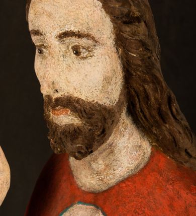 Zdjęcie nr 5: Pełnoplastyczna rzeźba ukazuje frontalnie w całej postaci zmartwychwstałego Chrystusa stojącego w kontrapoście na niewielkim wzgórku. Jego prawa noga jest nieco wysunięta i zgięta w kolanie. Zmartwychwstały unosi w geście zwycięstwa prawą rękę zgiętą w łokciu, lewą zaś uniesioną na wysokość piersi trzyma proporzec. Zbawiciel ma nieproporcjonalnie duże dłonie. Na rękach, stopach i boku widać ślady po męce. Chrystus ma mocno pociągłą twarz okoloną, krótkim, brązowym zarostem i brązowe włosy spływające na plecy. Jego twarz o jasnej karnacji charakteryzuje wysokie czoło, prosty nos i wydatne usta oraz szeroko otwarte ciemne oczy o spojrzeniu skierowanym przed siebie. Jezus ubrany jest w spięty pod szyją czerwony płaszcz podbity ciemną zielenią grynszpanową sięgający łydek z prawą połą podwiniętą przy lewym boku. Płaszcz odsłania mocno taliowany nagi tors z widocznym przebitym prawym bokiem.  