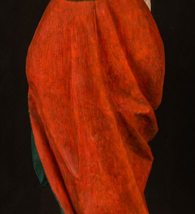 Zdjęcie nr 11: Pełnoplastyczna rzeźba ukazuje frontalnie w całej postaci zmartwychwstałego Chrystusa stojącego w kontrapoście na niewielkim wzgórku. Jego prawa noga jest nieco wysunięta i zgięta w kolanie. Zmartwychwstały unosi w geście zwycięstwa prawą rękę zgiętą w łokciu, lewą zaś uniesioną na wysokość piersi trzyma proporzec. Zbawiciel ma nieproporcjonalnie duże dłonie. Na rękach, stopach i boku widać ślady po męce. Chrystus ma mocno pociągłą twarz okoloną, krótkim, brązowym zarostem i brązowe włosy spływające na plecy. Jego twarz o jasnej karnacji charakteryzuje wysokie czoło, prosty nos i wydatne usta oraz szeroko otwarte ciemne oczy o spojrzeniu skierowanym przed siebie. Jezus ubrany jest w spięty pod szyją czerwony płaszcz podbity ciemną zielenią grynszpanową sięgający łydek z prawą połą podwiniętą przy lewym boku. Płaszcz odsłania mocno taliowany nagi tors z widocznym przebitym prawym bokiem.  