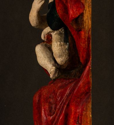 Zdjęcie nr 3: Rzeźba drążona, w pełni polichromowana. Pełnopostaciowe przedstawienie Marii karmiącej Dzieciątko Jezus. Matka Boska ukazana frontalnie, w pozycji siedzącej, trzyma na kolanach małego Jezusa, którego karmi piersią. Prawą ręką podtrzymuje Dzieciątko, lewą podaje mu pierś. Przedstawiona jako młoda kobieta o szerokiej, owalnej twarzy o wysokim czole i długich, ciemnych włosach. Oczy migdałowate, wpatrzone przed siebie. Cieńkie, łukowate brwi, niewielkie usta. Na głowie charakterystyczne podwyższenie – zapewne ślad po mocowaniu korony. Maria ubrana jest w ciemnogranatową, obcisłą suknię z długimi rękawami oraz czerwony płaszcz. Poła płaszcza okrywa również biodra Dzieciątka. Spod fałdów szat widoczne są czarne trzewiki o spiczastych noskach. Dzieciątko ukazane w pozycji siedzącej z głową uniesioną do góry, wyciągniętymi do przodu nóżkami i lewą ręką trzymającą pierś Marii. Twarz pełna z szeroko otwartymi oczami wpatrzonymi w matkę i zaróżowionymi policzkami. Włosy, krótkie, ciemne.