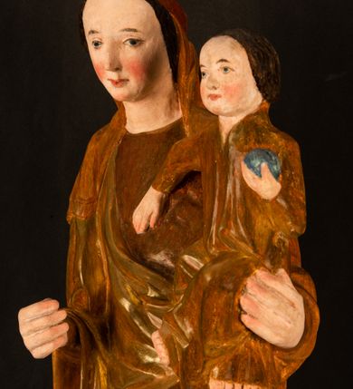 Zdjęcie nr 6: Rzeźba pełnoplastyczna, przyścienna, z tyłu wydrążona. Przedstawienie Matki Boskiej z Dzieciątkiem, ukazanej w całej postaci, frontalnie. Maria stoi w kontrapoście, esowato wygięta, z głową lekko przechyloną w lewo, podtrzymując Dzieciątko ręką wspartą na lewym biodrze. Twarz owalna, o subtelnych rysach, z wysokim czołem, regularnymi łukami brwiowymi i dużymi oczami, długim, wąskim nosem, małymi ustami i wydatnym podbródkiem. Ubrana w długą suknię i narzucony na ramiona płaszcz, przerzucony przez przód sylwetki i układający się poniżej piersi Marii sekwencją fałdów misowych i v-kształtnych. Na głowie źle zachowana chusta spływająca na ramiona. Dzieciątko siedzi na lewym przedramieniu Matki, ze skrzyżowanymi nóżkami, prawą dłonią dotykając piersi Marii, lewą trzyma glob. Twarz okrągła, o drobnych rysach, okolona krótkimi ciemnymi włosami. Jezus ubrany w długą sukienkę, spod której widać bose stopy.   