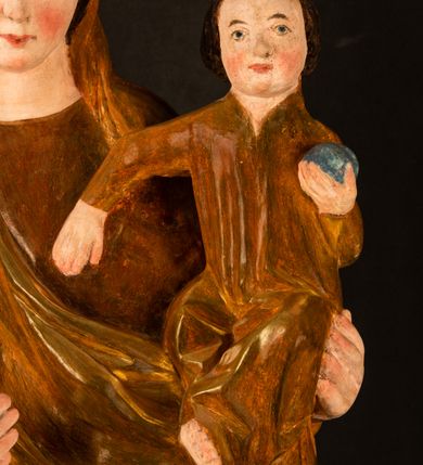 Zdjęcie nr 8: Rzeźba pełnoplastyczna, przyścienna, z tyłu wydrążona. Przedstawienie Matki Boskiej z Dzieciątkiem, ukazanej w całej postaci, frontalnie. Maria stoi w kontrapoście, esowato wygięta, z głową lekko przechyloną w lewo, podtrzymując Dzieciątko ręką wspartą na lewym biodrze. Twarz owalna, o subtelnych rysach, z wysokim czołem, regularnymi łukami brwiowymi i dużymi oczami, długim, wąskim nosem, małymi ustami i wydatnym podbródkiem. Ubrana w długą suknię i narzucony na ramiona płaszcz, przerzucony przez przód sylwetki i układający się poniżej piersi Marii sekwencją fałdów misowych i v-kształtnych. Na głowie źle zachowana chusta spływająca na ramiona. Dzieciątko siedzi na lewym przedramieniu Matki, ze skrzyżowanymi nóżkami, prawą dłonią dotykając piersi Marii, lewą trzyma glob. Twarz okrągła, o drobnych rysach, okolona krótkimi ciemnymi włosami. Jezus ubrany w długą sukienkę, spod której widać bose stopy.   