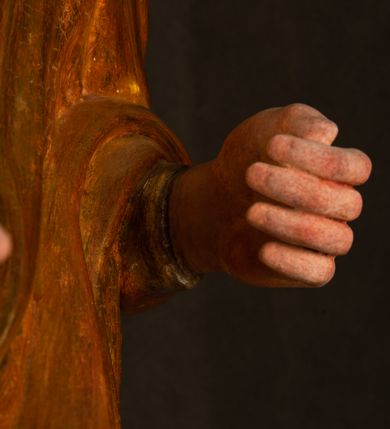 Zdjęcie nr 10: Rzeźba drążona, ustawiona na niewielkim, wielobocznym postumencie. Stojąca Maria ukazana frontalnie, w silnym kontrapoście z esowato wygiętym ciałem. Na lewej ręce podtrzymuje siedzące Dzieciątko, w prawej ręce ugiętej w łokciu i wyciągniętej do przodu najpewniej znajdowało się kiedyś berło.  Maria została ukazana jako młoda kobieta o owalnej twarzy, dużych, migdałowatych oczach, długim, prostym nosie i wyraźnie zaakcentowanych, dużych ustach. Karnacja jasna z rumieńcem zaznaczonym na policzkach i podbródku. Długie, jasne i falowane włosy częściowo zakryte chustą, symetrycznie okalają twarz postaci, spadając na jej ramiona. Maria jest ubrana w długą, sięgającą ziemi suknię, spod której widoczne są ostro zakończone czubki złotych butów oraz obszerny, złoty płaszcz tworzący ostro załamujące się fałdy na wysokości kolan Marii i formujący kaskadę wzdłuż prawego boku postaci. Na głowie Marii znajduje się biała chusta ze złota lamówką. Dzieciątko Jezus ukazane w pozycji siedzącej z lewą nogą wysuniętą wyraźnie do przodu. Prawą ręką wykonuje gest błogosławieństwa, w lewej trzyma niewielkie jabłko. Chłopiec o okrągłej, pulchnej twarzy i  krótkich, falowanych włosach spogląda przed siebie. Ubrany jest w wąską, suknię o długich rękawach, wykończoną przy dekolcie złotą lamówką. Spod sukni widoczne są bose stopy postaci. Karnacje postaci i część szat polichromowane, suknia Marii srebrzona, płaszcz i buty złocone.