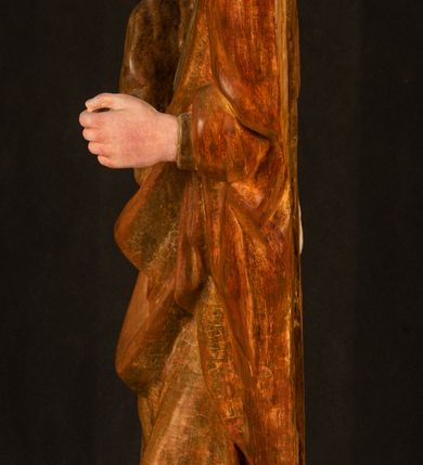 Zdjęcie nr 17: Rzeźba drążona, ustawiona na niewielkim, wielobocznym postumencie. Stojąca Maria ukazana frontalnie, w silnym kontrapoście z esowato wygiętym ciałem. Na lewej ręce podtrzymuje siedzące Dzieciątko, w prawej ręce ugiętej w łokciu i wyciągniętej do przodu najpewniej znajdowało się kiedyś berło.  Maria została ukazana jako młoda kobieta o owalnej twarzy, dużych, migdałowatych oczach, długim, prostym nosie i wyraźnie zaakcentowanych, dużych ustach. Karnacja jasna z rumieńcem zaznaczonym na policzkach i podbródku. Długie, jasne i falowane włosy częściowo zakryte chustą, symetrycznie okalają twarz postaci, spadając na jej ramiona. Maria jest ubrana w długą, sięgającą ziemi suknię, spod której widoczne są ostro zakończone czubki złotych butów oraz obszerny, złoty płaszcz tworzący ostro załamujące się fałdy na wysokości kolan Marii i formujący kaskadę wzdłuż prawego boku postaci. Na głowie Marii znajduje się biała chusta ze złota lamówką. Dzieciątko Jezus ukazane w pozycji siedzącej z lewą nogą wysuniętą wyraźnie do przodu. Prawą ręką wykonuje gest błogosławieństwa, w lewej trzyma niewielkie jabłko. Chłopiec o okrągłej, pulchnej twarzy i  krótkich, falowanych włosach spogląda przed siebie. Ubrany jest w wąską, suknię o długich rękawach, wykończoną przy dekolcie złotą lamówką. Spod sukni widoczne są bose stopy postaci. Karnacje postaci i część szat polichromowane, suknia Marii srebrzona, płaszcz i buty złocone.