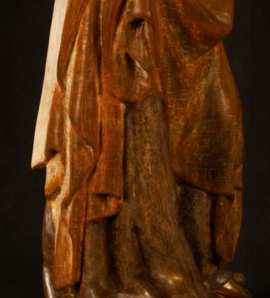 Zdjęcie nr 7: Rzeźba drążona, ustawiona na niewielkim, wielobocznym postumencie. Stojąca Maria ukazana frontalnie, w silnym kontrapoście z esowato wygiętym ciałem. Na lewej ręce podtrzymuje siedzące Dzieciątko, w prawej ręce ugiętej w łokciu i wyciągniętej do przodu najpewniej znajdowało się kiedyś berło.  Maria została ukazana jako młoda kobieta o owalnej twarzy, dużych, migdałowatych oczach, długim, prostym nosie i wyraźnie zaakcentowanych, dużych ustach. Karnacja jasna z rumieńcem zaznaczonym na policzkach i podbródku. Długie, jasne i falowane włosy częściowo zakryte chustą, symetrycznie okalają twarz postaci, spadając na jej ramiona. Maria jest ubrana w długą, sięgającą ziemi suknię, spod której widoczne są ostro zakończone czubki złotych butów oraz obszerny, złoty płaszcz tworzący ostro załamujące się fałdy na wysokości kolan Marii i formujący kaskadę wzdłuż prawego boku postaci. Na głowie Marii znajduje się biała chusta ze złota lamówką. Dzieciątko Jezus ukazane w pozycji siedzącej z lewą nogą wysuniętą wyraźnie do przodu. Prawą ręką wykonuje gest błogosławieństwa, w lewej trzyma niewielkie jabłko. Chłopiec o okrągłej, pulchnej twarzy i  krótkich, falowanych włosach spogląda przed siebie. Ubrany jest w wąską, suknię o długich rękawach, wykończoną przy dekolcie złotą lamówką. Spod sukni widoczne są bose stopy postaci. Karnacje postaci i część szat polichromowane, suknia Marii srebrzona, płaszcz i buty złocone.