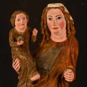 Zdjęcie nr 1: Rzeźba drążona, ustawiona na niewielkim, wielobocznym postumencie. Stojąca Maria ukazana frontalnie, w silnym kontrapoście z esowato wygiętym ciałem. Na lewej ręce podtrzymuje siedzące Dzieciątko, w prawej ręce ugiętej w łokciu i wyciągniętej do przodu najpewniej znajdowało się kiedyś berło.  Maria została ukazana jako młoda kobieta o owalnej twarzy, dużych, migdałowatych oczach, długim, prostym nosie i wyraźnie zaakcentowanych, dużych ustach. Karnacja jasna z rumieńcem zaznaczonym na policzkach i podbródku. Długie, jasne i falowane włosy częściowo zakryte chustą, symetrycznie okalają twarz postaci, spadając na jej ramiona. Maria jest ubrana w długą, sięgającą ziemi suknię, spod której widoczne są ostro zakończone czubki złotych butów oraz obszerny, złoty płaszcz tworzący ostro załamujące się fałdy na wysokości kolan Marii i formujący kaskadę wzdłuż prawego boku postaci. Na głowie Marii znajduje się biała chusta ze złota lamówką. Dzieciątko Jezus ukazane w pozycji siedzącej z lewą nogą wysuniętą wyraźnie do przodu. Prawą ręką wykonuje gest błogosławieństwa, w lewej trzyma niewielkie jabłko. Chłopiec o okrągłej, pulchnej twarzy i  krótkich, falowanych włosach spogląda przed siebie. Ubrany jest w wąską, suknię o długich rękawach, wykończoną przy dekolcie złotą lamówką. Spod sukni widoczne są bose stopy postaci. Karnacje postaci i część szat polichromowane, suknia Marii srebrzona, płaszcz i buty złocone.