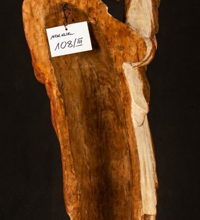 Zdjęcie nr 21: Rzeźba drążona, ustawiona na niewielkim, wielobocznym postumencie. Stojąca Maria ukazana frontalnie, w silnym kontrapoście z esowato wygiętym ciałem. Na lewej ręce podtrzymuje siedzące Dzieciątko, w prawej ręce ugiętej w łokciu i wyciągniętej do przodu najpewniej znajdowało się kiedyś berło.  Maria została ukazana jako młoda kobieta o owalnej twarzy, dużych, migdałowatych oczach, długim, prostym nosie i wyraźnie zaakcentowanych, dużych ustach. Karnacja jasna z rumieńcem zaznaczonym na policzkach i podbródku. Długie, jasne i falowane włosy częściowo zakryte chustą, symetrycznie okalają twarz postaci, spadając na jej ramiona. Maria jest ubrana w długą, sięgającą ziemi suknię, spod której widoczne są ostro zakończone czubki złotych butów oraz obszerny, złoty płaszcz tworzący ostro załamujące się fałdy na wysokości kolan Marii i formujący kaskadę wzdłuż prawego boku postaci. Na głowie Marii znajduje się biała chusta ze złota lamówką. Dzieciątko Jezus ukazane w pozycji siedzącej z lewą nogą wysuniętą wyraźnie do przodu. Prawą ręką wykonuje gest błogosławieństwa, w lewej trzyma niewielkie jabłko. Chłopiec o okrągłej, pulchnej twarzy i  krótkich, falowanych włosach spogląda przed siebie. Ubrany jest w wąską, suknię o długich rękawach, wykończoną przy dekolcie złotą lamówką. Spod sukni widoczne są bose stopy postaci. Karnacje postaci i część szat polichromowane, suknia Marii srebrzona, płaszcz i buty złocone.