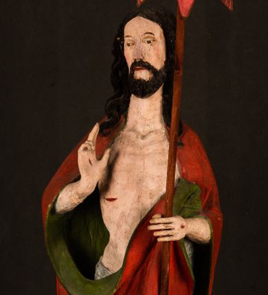 Zdjęcie nr 1: Rzeźba pełna, ustawiona na podstawie na planie ośmioboku oraz na fragmencie podłoża. Chrystus ukazany w całej postaci, frontalnie, prawą, ugiętą rękę unosi w geście błogosławieństwa, lewą trzyma z przodu drzewce chorągwi. Twarz ma podłużną, o migdałowatych, półprzymkniętych oczach, prostym, długim nosie i wąskich ustach. Twarz okolona krótką ciemną brodą oraz falowanymi włosami, opadającymi na ramiona. Przez biodra ma przewiązane białe perizonium, przylegające go ciała. Na ramiona ma narzucony czerwony płaszcz z zieloną podszewką, zawinięty łukowato z przodu postaci i przytrzymywany lewą ręką. Ciało ma wychudzone, o silnie podkreślonych żebrach klatki piersiowej oraz wcięciu w talii, z zaznaczonymi śladami męki. Polichromia ciała naturalistyczna, o jasnej karnacji. Chorągiew wykonana z czerwonej tkaniny wielkowzorzystej. 