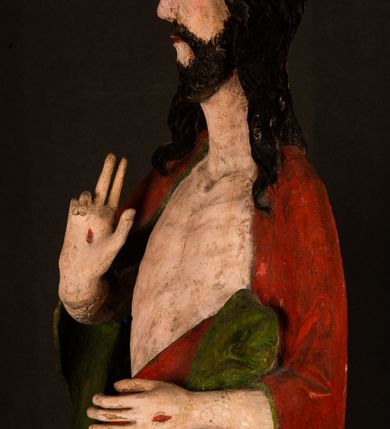 Zdjęcie nr 9: Rzeźba pełna, ustawiona na podstawie na planie ośmioboku oraz na fragmencie podłoża. Chrystus ukazany w całej postaci, frontalnie, prawą, ugiętą rękę unosi w geście błogosławieństwa, lewą trzyma z przodu drzewce chorągwi. Twarz ma podłużną, o migdałowatych, półprzymkniętych oczach, prostym, długim nosie i wąskich ustach. Twarz okolona krótką ciemną brodą oraz falowanymi włosami, opadającymi na ramiona. Przez biodra ma przewiązane białe perizonium, przylegające go ciała. Na ramiona ma narzucony czerwony płaszcz z zieloną podszewką, zawinięty łukowato z przodu postaci i przytrzymywany lewą ręką. Ciało ma wychudzone, o silnie podkreślonych żebrach klatki piersiowej oraz wcięciu w talii, z zaznaczonymi śladami męki. Polichromia ciała naturalistyczna, o jasnej karnacji. Chorągiew wykonana z czerwonej tkaniny wielkowzorzystej. 