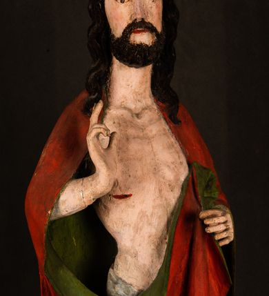 Zdjęcie nr 8: Rzeźba pełna, ustawiona na podstawie na planie ośmioboku oraz na fragmencie podłoża. Chrystus ukazany w całej postaci, frontalnie, prawą, ugiętą rękę unosi w geście błogosławieństwa, lewą trzyma z przodu drzewce chorągwi. Twarz ma podłużną, o migdałowatych, półprzymkniętych oczach, prostym, długim nosie i wąskich ustach. Twarz okolona krótką ciemną brodą oraz falowanymi włosami, opadającymi na ramiona. Przez biodra ma przewiązane białe perizonium, przylegające go ciała. Na ramiona ma narzucony czerwony płaszcz z zieloną podszewką, zawinięty łukowato z przodu postaci i przytrzymywany lewą ręką. Ciało ma wychudzone, o silnie podkreślonych żebrach klatki piersiowej oraz wcięciu w talii, z zaznaczonymi śladami męki. Polichromia ciała naturalistyczna, o jasnej karnacji. Chorągiew wykonana z czerwonej tkaniny wielkowzorzystej. 