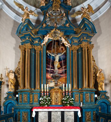 Zdjęcie nr 2: Ołtarz architektoniczny, jednoosiowy, jednokondygnacyjny ze zwieńczeniem. Na zdwojonych cokołach usytuowanych ukośnie względem osi po trzy kompozytowe kolumny opinające filary o gładkich trzonach podtrzymujących wyłamujące się nad nimi belkowanie z ćwierćkolistymi naczółkami. Na nich siedzące anioły z narzędzami męki Pańskiej. Pośrodku wnęka zamknięta półkoliście i wchodząca w partię belkowania z figurą Ukrzyżowanego. Nad wnęką dwa nagie putta trzymają kartusz z napisem: "DZIEŁO / NIE MAJĄC PRZYKŁADU / ŁASKA NIE ZASŁUŻONA / DAR NIE OCENIONY / MIŁOŚĆ BEZ GRANIC".  Zwieńczenie ujęte spływami wolutowymi, mocno zwężające się ku górze, zakończone gzymsem w formie łuku nadwieszonego. W polu owalny prześwit z glorią promienistą w chmurach z figurą Boga Ojca, puttami siedzącymi na gzymsie i główkami aniołów wśród chmur. Po bokach ołtarza dwie bramki z cokołami ujętymi spływami wolutowymi, na których figury św. Jana Chrzciciela i św. Jana Ewangelisty. Dekoracja ornamentalna w postaci rozłożystych liści na cokołach oraz liściastych, ażurowych uszy ujmujących nastawę. 