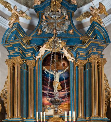 Zdjęcie nr 38: Ołtarz architektoniczny, jednoosiowy, jednokondygnacyjny ze zwieńczeniem. Na zdwojonych cokołach usytuowanych ukośnie względem osi po trzy kompozytowe kolumny opinające filary o gładkich trzonach podtrzymujących wyłamujące się nad nimi belkowanie z ćwierćkolistymi naczółkami. Na nich siedzące anioły z narzędzami męki Pańskiej. Pośrodku wnęka zamknięta półkoliście i wchodząca w partię belkowania z figurą Ukrzyżowanego. Nad wnęką dwa nagie putta trzymają kartusz z napisem: &quot;DZIEŁO / NIE MAJĄC PRZYKŁADU / ŁASKA NIE ZASŁUŻONA / DAR NIE OCENIONY / MIŁOŚĆ BEZ GRANIC&quot;.  Zwieńczenie ujęte spływami wolutowymi, mocno zwężające się ku górze, zakończone gzymsem w formie łuku nadwieszonego. W polu owalny prześwit z glorią promienistą w chmurach z figurą Boga Ojca, puttami siedzącymi na gzymsie i główkami aniołów wśród chmur. Po bokach ołtarza dwie bramki z cokołami ujętymi spływami wolutowymi, na których figury św. Jana Chrzciciela i św. Jana Ewangelisty. Dekoracja ornamentalna w postaci rozłożystych liści na cokołach oraz liściastych, ażurowych uszy ujmujących nastawę. 