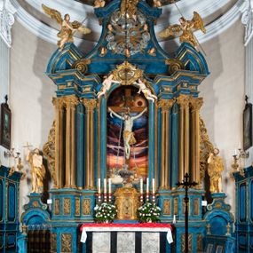 Zdjęcie nr 1: Ołtarz architektoniczny, jednoosiowy, jednokondygnacyjny ze zwieńczeniem. Na zdwojonych cokołach usytuowanych ukośnie względem osi po trzy kompozytowe kolumny opinające filary o gładkich trzonach podtrzymujących wyłamujące się nad nimi belkowanie z ćwierćkolistymi naczółkami. Na nich siedzące anioły z narzędzami męki Pańskiej. Pośrodku wnęka zamknięta półkoliście i wchodząca w partię belkowania z figurą Ukrzyżowanego. Nad wnęką dwa nagie putta trzymają kartusz z napisem: "DZIEŁO / NIE MAJĄC PRZYKŁADU / ŁASKA NIE ZASŁUŻONA / DAR NIE OCENIONY / MIŁOŚĆ BEZ GRANIC".  Zwieńczenie ujęte spływami wolutowymi, mocno zwężające się ku górze, zakończone gzymsem w formie łuku nadwieszonego. W polu owalny prześwit z glorią promienistą w chmurach z figurą Boga Ojca, puttami siedzącymi na gzymsie i główkami aniołów wśród chmur. Po bokach ołtarza dwie bramki z cokołami ujętymi spływami wolutowymi, na których figury św. Jana Chrzciciela i św. Jana Ewangelisty. Dekoracja ornamentalna w postaci rozłożystych liści na cokołach oraz liściastych, ażurowych uszy ujmujących nastawę. 