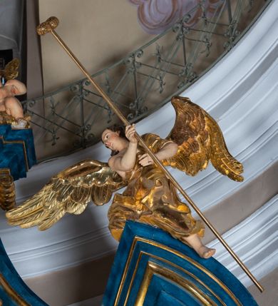 Zdjęcie nr 19: Ołtarz architektoniczny, jednoosiowy, jednokondygnacyjny ze zwieńczeniem. Na zdwojonych cokołach usytuowanych ukośnie względem osi po trzy kompozytowe kolumny opinające filary o gładkich trzonach podtrzymujących wyłamujące się nad nimi belkowanie z ćwierćkolistymi naczółkami. Na nich siedzące anioły z narzędzami męki Pańskiej. Pośrodku wnęka zamknięta półkoliście i wchodząca w partię belkowania z figurą Ukrzyżowanego. Nad wnęką dwa nagie putta trzymają kartusz z napisem: &quot;DZIEŁO / NIE MAJĄC PRZYKŁADU / ŁASKA NIE ZASŁUŻONA / DAR NIE OCENIONY / MIŁOŚĆ BEZ GRANIC&quot;.  Zwieńczenie ujęte spływami wolutowymi, mocno zwężające się ku górze, zakończone gzymsem w formie łuku nadwieszonego. W polu owalny prześwit z glorią promienistą w chmurach z figurą Boga Ojca, puttami siedzącymi na gzymsie i główkami aniołów wśród chmur. Po bokach ołtarza dwie bramki z cokołami ujętymi spływami wolutowymi, na których figury św. Jana Chrzciciela i św. Jana Ewangelisty. Dekoracja ornamentalna w postaci rozłożystych liści na cokołach oraz liściastych, ażurowych uszy ujmujących nastawę. 