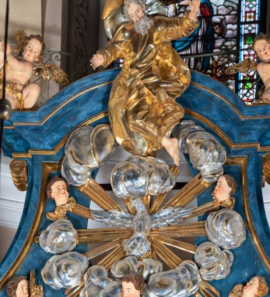 Zdjęcie nr 28: Ołtarz architektoniczny, jednoosiowy, jednokondygnacyjny ze zwieńczeniem. Na zdwojonych cokołach usytuowanych ukośnie względem osi po trzy kompozytowe kolumny opinające filary o gładkich trzonach podtrzymujących wyłamujące się nad nimi belkowanie z ćwierćkolistymi naczółkami. Na nich siedzące anioły z narzędzami męki Pańskiej. Pośrodku wnęka zamknięta półkoliście i wchodząca w partię belkowania z figurą Ukrzyżowanego. Nad wnęką dwa nagie putta trzymają kartusz z napisem: "DZIEŁO / NIE MAJĄC PRZYKŁADU / ŁASKA NIE ZASŁUŻONA / DAR NIE OCENIONY / MIŁOŚĆ BEZ GRANIC".  Zwieńczenie ujęte spływami wolutowymi, mocno zwężające się ku górze, zakończone gzymsem w formie łuku nadwieszonego. W polu owalny prześwit z glorią promienistą w chmurach z figurą Boga Ojca, puttami siedzącymi na gzymsie i główkami aniołów wśród chmur. Po bokach ołtarza dwie bramki z cokołami ujętymi spływami wolutowymi, na których figury św. Jana Chrzciciela i św. Jana Ewangelisty. Dekoracja ornamentalna w postaci rozłożystych liści na cokołach oraz liściastych, ażurowych uszy ujmujących nastawę. 