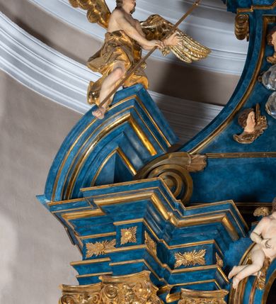 Zdjęcie nr 25: Ołtarz architektoniczny, jednoosiowy, jednokondygnacyjny ze zwieńczeniem. Na zdwojonych cokołach usytuowanych ukośnie względem osi po trzy kompozytowe kolumny opinające filary o gładkich trzonach podtrzymujących wyłamujące się nad nimi belkowanie z ćwierćkolistymi naczółkami. Na nich siedzące anioły z narzędzami męki Pańskiej. Pośrodku wnęka zamknięta półkoliście i wchodząca w partię belkowania z figurą Ukrzyżowanego. Nad wnęką dwa nagie putta trzymają kartusz z napisem: "DZIEŁO / NIE MAJĄC PRZYKŁADU / ŁASKA NIE ZASŁUŻONA / DAR NIE OCENIONY / MIŁOŚĆ BEZ GRANIC".  Zwieńczenie ujęte spływami wolutowymi, mocno zwężające się ku górze, zakończone gzymsem w formie łuku nadwieszonego. W polu owalny prześwit z glorią promienistą w chmurach z figurą Boga Ojca, puttami siedzącymi na gzymsie i główkami aniołów wśród chmur. Po bokach ołtarza dwie bramki z cokołami ujętymi spływami wolutowymi, na których figury św. Jana Chrzciciela i św. Jana Ewangelisty. Dekoracja ornamentalna w postaci rozłożystych liści na cokołach oraz liściastych, ażurowych uszy ujmujących nastawę. 