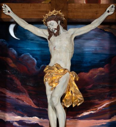 Zdjęcie nr 40: Ołtarz architektoniczny, jednoosiowy, jednokondygnacyjny ze zwieńczeniem. Na zdwojonych cokołach usytuowanych ukośnie względem osi po trzy kompozytowe kolumny opinające filary o gładkich trzonach podtrzymujących wyłamujące się nad nimi belkowanie z ćwierćkolistymi naczółkami. Na nich siedzące anioły z narzędzami męki Pańskiej. Pośrodku wnęka zamknięta półkoliście i wchodząca w partię belkowania z figurą Ukrzyżowanego. Nad wnęką dwa nagie putta trzymają kartusz z napisem: &quot;DZIEŁO / NIE MAJĄC PRZYKŁADU / ŁASKA NIE ZASŁUŻONA / DAR NIE OCENIONY / MIŁOŚĆ BEZ GRANIC&quot;.  Zwieńczenie ujęte spływami wolutowymi, mocno zwężające się ku górze, zakończone gzymsem w formie łuku nadwieszonego. W polu owalny prześwit z glorią promienistą w chmurach z figurą Boga Ojca, puttami siedzącymi na gzymsie i główkami aniołów wśród chmur. Po bokach ołtarza dwie bramki z cokołami ujętymi spływami wolutowymi, na których figury św. Jana Chrzciciela i św. Jana Ewangelisty. Dekoracja ornamentalna w postaci rozłożystych liści na cokołach oraz liściastych, ażurowych uszy ujmujących nastawę. 