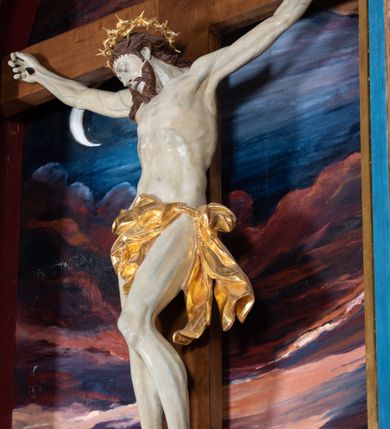 Zdjęcie nr 41: Ołtarz architektoniczny, jednoosiowy, jednokondygnacyjny ze zwieńczeniem. Na zdwojonych cokołach usytuowanych ukośnie względem osi po trzy kompozytowe kolumny opinające filary o gładkich trzonach podtrzymujących wyłamujące się nad nimi belkowanie z ćwierćkolistymi naczółkami. Na nich siedzące anioły z narzędzami męki Pańskiej. Pośrodku wnęka zamknięta półkoliście i wchodząca w partię belkowania z figurą Ukrzyżowanego. Nad wnęką dwa nagie putta trzymają kartusz z napisem: "DZIEŁO / NIE MAJĄC PRZYKŁADU / ŁASKA NIE ZASŁUŻONA / DAR NIE OCENIONY / MIŁOŚĆ BEZ GRANIC".  Zwieńczenie ujęte spływami wolutowymi, mocno zwężające się ku górze, zakończone gzymsem w formie łuku nadwieszonego. W polu owalny prześwit z glorią promienistą w chmurach z figurą Boga Ojca, puttami siedzącymi na gzymsie i główkami aniołów wśród chmur. Po bokach ołtarza dwie bramki z cokołami ujętymi spływami wolutowymi, na których figury św. Jana Chrzciciela i św. Jana Ewangelisty. Dekoracja ornamentalna w postaci rozłożystych liści na cokołach oraz liściastych, ażurowych uszy ujmujących nastawę. 