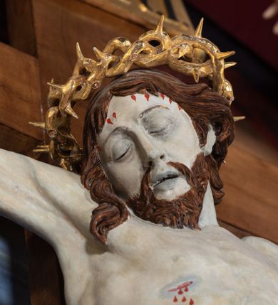 Zdjęcie nr 45: Ołtarz architektoniczny, jednoosiowy, jednokondygnacyjny ze zwieńczeniem. Na zdwojonych cokołach usytuowanych ukośnie względem osi po trzy kompozytowe kolumny opinające filary o gładkich trzonach podtrzymujących wyłamujące się nad nimi belkowanie z ćwierćkolistymi naczółkami. Na nich siedzące anioły z narzędzami męki Pańskiej. Pośrodku wnęka zamknięta półkoliście i wchodząca w partię belkowania z figurą Ukrzyżowanego. Nad wnęką dwa nagie putta trzymają kartusz z napisem: &quot;DZIEŁO / NIE MAJĄC PRZYKŁADU / ŁASKA NIE ZASŁUŻONA / DAR NIE OCENIONY / MIŁOŚĆ BEZ GRANIC&quot;.  Zwieńczenie ujęte spływami wolutowymi, mocno zwężające się ku górze, zakończone gzymsem w formie łuku nadwieszonego. W polu owalny prześwit z glorią promienistą w chmurach z figurą Boga Ojca, puttami siedzącymi na gzymsie i główkami aniołów wśród chmur. Po bokach ołtarza dwie bramki z cokołami ujętymi spływami wolutowymi, na których figury św. Jana Chrzciciela i św. Jana Ewangelisty. Dekoracja ornamentalna w postaci rozłożystych liści na cokołach oraz liściastych, ażurowych uszy ujmujących nastawę. 