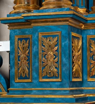 Zdjęcie nr 78: Ołtarz architektoniczny, jednoosiowy, jednokondygnacyjny ze zwieńczeniem. Na zdwojonych cokołach usytuowanych ukośnie względem osi po trzy kompozytowe kolumny opinające filary o gładkich trzonach podtrzymujących wyłamujące się nad nimi belkowanie z ćwierćkolistymi naczółkami. Na nich siedzące anioły z narzędzami męki Pańskiej. Pośrodku wnęka zamknięta półkoliście i wchodząca w partię belkowania z figurą Ukrzyżowanego. Nad wnęką dwa nagie putta trzymają kartusz z napisem: &quot;DZIEŁO / NIE MAJĄC PRZYKŁADU / ŁASKA NIE ZASŁUŻONA / DAR NIE OCENIONY / MIŁOŚĆ BEZ GRANIC&quot;.  Zwieńczenie ujęte spływami wolutowymi, mocno zwężające się ku górze, zakończone gzymsem w formie łuku nadwieszonego. W polu owalny prześwit z glorią promienistą w chmurach z figurą Boga Ojca, puttami siedzącymi na gzymsie i główkami aniołów wśród chmur. Po bokach ołtarza dwie bramki z cokołami ujętymi spływami wolutowymi, na których figury św. Jana Chrzciciela i św. Jana Ewangelisty. Dekoracja ornamentalna w postaci rozłożystych liści na cokołach oraz liściastych, ażurowych uszy ujmujących nastawę. 