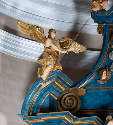 Zdjęcie nr 88: Ołtarz architektoniczny, jednoosiowy, jednokondygnacyjny ze zwieńczeniem. Na zdwojonych cokołach usytuowanych ukośnie względem osi po trzy kompozytowe kolumny opinające filary o gładkich trzonach podtrzymujących wyłamujące się nad nimi belkowanie z ćwierćkolistymi naczółkami. Na nich siedzące anioły z narzędzami męki Pańskiej. Pośrodku wnęka zamknięta półkoliście i wchodząca w partię belkowania z figurą Ukrzyżowanego. Nad wnęką dwa nagie putta trzymają kartusz z napisem: "DZIEŁO / NIE MAJĄC PRZYKŁADU / ŁASKA NIE ZASŁUŻONA / DAR NIE OCENIONY / MIŁOŚĆ BEZ GRANIC".  Zwieńczenie ujęte spływami wolutowymi, mocno zwężające się ku górze, zakończone gzymsem w formie łuku nadwieszonego. W polu owalny prześwit z glorią promienistą w chmurach z figurą Boga Ojca, puttami siedzącymi na gzymsie i główkami aniołów wśród chmur. Po bokach ołtarza dwie bramki z cokołami ujętymi spływami wolutowymi, na których figury św. Jana Chrzciciela i św. Jana Ewangelisty. Dekoracja ornamentalna w postaci rozłożystych liści na cokołach oraz liściastych, ażurowych uszy ujmujących nastawę. 