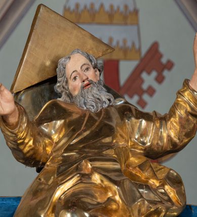 Zdjęcie nr 95: Ołtarz architektoniczny, jednoosiowy, jednokondygnacyjny ze zwieńczeniem. Na zdwojonych cokołach usytuowanych ukośnie względem osi po trzy kompozytowe kolumny opinające filary o gładkich trzonach podtrzymujących wyłamujące się nad nimi belkowanie z ćwierćkolistymi naczółkami. Na nich siedzące anioły z narzędzami męki Pańskiej. Pośrodku wnęka zamknięta półkoliście i wchodząca w partię belkowania z figurą Ukrzyżowanego. Nad wnęką dwa nagie putta trzymają kartusz z napisem: "DZIEŁO / NIE MAJĄC PRZYKŁADU / ŁASKA NIE ZASŁUŻONA / DAR NIE OCENIONY / MIŁOŚĆ BEZ GRANIC".  Zwieńczenie ujęte spływami wolutowymi, mocno zwężające się ku górze, zakończone gzymsem w formie łuku nadwieszonego. W polu owalny prześwit z glorią promienistą w chmurach z figurą Boga Ojca, puttami siedzącymi na gzymsie i główkami aniołów wśród chmur. Po bokach ołtarza dwie bramki z cokołami ujętymi spływami wolutowymi, na których figury św. Jana Chrzciciela i św. Jana Ewangelisty. Dekoracja ornamentalna w postaci rozłożystych liści na cokołach oraz liściastych, ażurowych uszy ujmujących nastawę. 