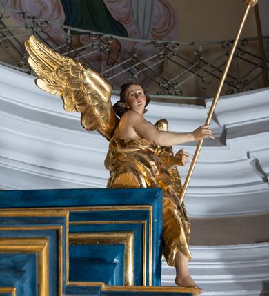 Zdjęcie nr 102: Ołtarz architektoniczny, jednoosiowy, jednokondygnacyjny ze zwieńczeniem. Na zdwojonych cokołach usytuowanych ukośnie względem osi po trzy kompozytowe kolumny opinające filary o gładkich trzonach podtrzymujących wyłamujące się nad nimi belkowanie z ćwierćkolistymi naczółkami. Na nich siedzące anioły z narzędzami męki Pańskiej. Pośrodku wnęka zamknięta półkoliście i wchodząca w partię belkowania z figurą Ukrzyżowanego. Nad wnęką dwa nagie putta trzymają kartusz z napisem: "DZIEŁO / NIE MAJĄC PRZYKŁADU / ŁASKA NIE ZASŁUŻONA / DAR NIE OCENIONY / MIŁOŚĆ BEZ GRANIC".  Zwieńczenie ujęte spływami wolutowymi, mocno zwężające się ku górze, zakończone gzymsem w formie łuku nadwieszonego. W polu owalny prześwit z glorią promienistą w chmurach z figurą Boga Ojca, puttami siedzącymi na gzymsie i główkami aniołów wśród chmur. Po bokach ołtarza dwie bramki z cokołami ujętymi spływami wolutowymi, na których figury św. Jana Chrzciciela i św. Jana Ewangelisty. Dekoracja ornamentalna w postaci rozłożystych liści na cokołach oraz liściastych, ażurowych uszy ujmujących nastawę. 