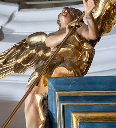 Zdjęcie nr 5: Ołtarz architektoniczny, jednoosiowy, jednokondygnacyjny ze zwieńczeniem. Na zdwojonych cokołach usytuowanych ukośnie względem osi po trzy kompozytowe kolumny opinające filary o gładkich trzonach podtrzymujących wyłamujące się nad nimi belkowanie z ćwierćkolistymi naczółkami. Na nich siedzące anioły z narzędzami męki Pańskiej. Pośrodku wnęka zamknięta półkoliście i wchodząca w partię belkowania z figurą Ukrzyżowanego. Nad wnęką dwa nagie putta trzymają kartusz z napisem: &quot;DZIEŁO / NIE MAJĄC PRZYKŁADU / ŁASKA NIE ZASŁUŻONA / DAR NIE OCENIONY / MIŁOŚĆ BEZ GRANIC&quot;.  Zwieńczenie ujęte spływami wolutowymi, mocno zwężające się ku górze, zakończone gzymsem w formie łuku nadwieszonego. W polu owalny prześwit z glorią promienistą w chmurach z figurą Boga Ojca, puttami siedzącymi na gzymsie i główkami aniołów wśród chmur. Po bokach ołtarza dwie bramki z cokołami ujętymi spływami wolutowymi, na których figury św. Jana Chrzciciela i św. Jana Ewangelisty. Dekoracja ornamentalna w postaci rozłożystych liści na cokołach oraz liściastych, ażurowych uszy ujmujących nastawę. 