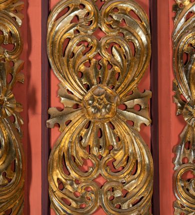 Zdjęcie nr 6: Ambona przyścienna dostępna jednotraktraktowymi schodami z pełną balustradą od strony wschodniej. Kosz na rzucie owalnym, opięty dostawionymi do boków pilastrami na rzucie trójkąta. W dolnej części złocony z podwieszoną szyszką. Podstawa walcowato wypukła dekorowana suchym akantem i jajownikiem. W polach kosza płyciny w kształcie stojącego prostokąta z symetryczną, złoconą dekoracją akantową. Trzony pilastrów wypełnione złoconym akantem o esowatym przebiegu wici. W zwieńczeniu wypukły, profilowany gzyms dekorowany palmetami I jajownikiem. Balustrada schodów zakończona pilastrem z prostokątną płyciną. W polu złocona dekoracją z suchego akantu. Struktura malowana w odcieniach ciemnej czerwieni i brązu, ornamentyka złocona.