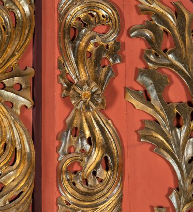 Zdjęcie nr 8: Ambona przyścienna dostępna jednotraktraktowymi schodami z pełną balustradą od strony wschodniej. Kosz na rzucie owalnym, opięty dostawionymi do boków pilastrami na rzucie trójkąta. W dolnej części złocony z podwieszoną szyszką. Podstawa walcowato wypukła dekorowana suchym akantem i jajownikiem. W polach kosza płyciny w kształcie stojącego prostokąta z symetryczną, złoconą dekoracją akantową. Trzony pilastrów wypełnione złoconym akantem o esowatym przebiegu wici. W zwieńczeniu wypukły, profilowany gzyms dekorowany palmetami I jajownikiem. Balustrada schodów zakończona pilastrem z prostokątną płyciną. W polu złocona dekoracją z suchego akantu. Struktura malowana w odcieniach ciemnej czerwieni i brązu, ornamentyka złocona.