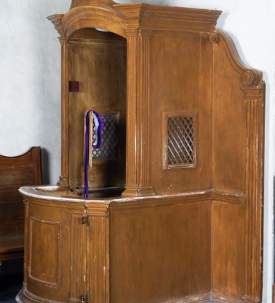 Zdjęcie nr 2: Konfesjonał ustawiony na jednostopniowym podwyższeniu, ujęty po bokach ściankami zakończonymi spływami wolutowymi oraz pilastrami o kanelowanych trzonach i prostych kapitelach. Przedpiersie o linii wypukłej dekorowane prostokątną płyciną ujętą zdwojonymi pilastrami i zwieńczone profilowanym gzymsem. Siedzisko z pilastrami po bokach podtrzymującymi łukowato wygięty w osi, profilowany architraw, na którym zwieńczenie o wklęsłych bokach zakończone profilowanym gzymsem o wolutowych zakończeniach. Zaplecek gładki. Struktura malowana w kolorze brązowym.