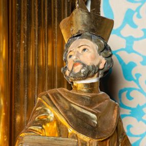 Zdjęcie nr 1: Rzeźba ścięta z tyłu, ustawiona na cokole. Święty ukazany frontalnie, w kontrapoście, z głową skierowaną w prawo. Lewą rękę ma opuszczonĄ w dół, prawą podtrzymuje zamkniętĄ księgę. Twarz ma kwadratową, o dużych, migdałowatych oczach, krótkim, prostym nosie i wąskich ustach, okolonĄ krótkimi, kręconymi włosami i brodą. Na głowie ma biret. Ubrany jest w togę profesorską o szerokich rękawach, z załogą (pelerynką). Polichromia ciała naturalistyczna, szaty i atrybuty złocone. 
