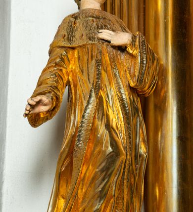 Zdjęcie nr 7: Rzeźba ścięta z tyłu, ustawiona na cokole. Święty ukazany frontalnie, w kontrapoście, z głową skierowaną w lewo. Prawą rękę ma opuszczoną, lewa spoczywa na piersi. Twarz ma kwadratową, o wyodrębnionej brodzie, młodzieńczych rysach, dużych, migdałowatych oczach, krótkim, prostym nosie i wąskich, rozchylonych ustach, okoloną krótkimi, kręconymi, brązowymi włosami. Na głowie ma mitrę książęcą. Ubrany jest w długą tunikę oraz rozchylony z przodu płaszcz królewski, o szerokich rękawach, z gronostajową pelerynką. Polichromia w partiach ciała naturalistyczna, szaty złocone. 

