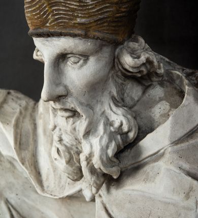 Zdjęcie nr 4: Rzeźba w całej postaci ukazuje frontalnie św. Augustyna ujętego w mocnym kontrapoście. Święty podniesioną prawą ręką trzyma pastorał, lewą zaś zdaje się odbierać rybę podawana mu przez nagie putto widniejące u jego stóp. Biskup w wysokiej infule ma pociągłą twarz o zapadniętych policzkach otoczoną rozwianą, długa brodą oraz kędzierzawymi włosami wystającymi spod złoconej infuły. Jego twarz charakteryzuje wydatny nos i usta. Ubrany jest w rozwianą mocno drapowaną sutannę, komżę obszytą u spodu frędzlą oraz kapę spiętą pod szyją. Spod sutanny widoczny jest stopa obuta w trzewik. Nagie putto u stóp biskua zostało ukazane w kontrapoście w trzech czwartych w prawo. Obiema rękami podaje świętemu rybę. Fragment jego biodra zasłani rozwiana tkanina. Putto wraz z biskupem stoją na fragmencie brzegu. 