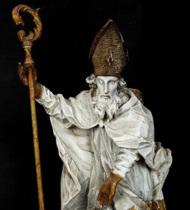 Zdjęcie nr 1: Rzeźba w całej postaci ukazuje frontalnie św. Augustyna ujętego w mocnym kontrapoście. Święty podniesioną prawą ręką trzyma pastorał, lewą zaś zdaje się odbierać rybę podawana mu przez nagie putto widniejące u jego stóp. Biskup w wysokiej infule ma pociągłą twarz o zapadniętych policzkach otoczoną rozwianą, długa brodą oraz kędzierzawymi włosami wystającymi spod złoconej infuły. Jego twarz charakteryzuje wydatny nos i usta. Ubrany jest w rozwianą mocno drapowaną sutannę, komżę obszytą u spodu frędzlą oraz kapę spiętą pod szyją. Spod sutanny widoczny jest stopa obuta w trzewik. Nagie putto u stóp biskua zostało ukazane w kontrapoście w trzech czwartych w prawo. Obiema rękami podaje świętemu rybę. Fragment jego biodra zasłani rozwiana tkanina. Putto wraz z biskupem stoją na fragmencie brzegu. 