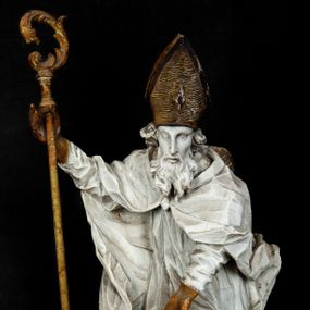 Zdjęcie nr 1: Rzeźba w całej postaci ukazuje frontalnie św. Augustyna ujętego w mocnym kontrapoście. Święty podniesioną prawą ręką trzyma pastorał, lewą zaś zdaje się odbierać rybę podawana mu przez nagie putto widniejące u jego stóp. Biskup w wysokiej infule ma pociągłą twarz o zapadniętych policzkach otoczoną rozwianą, długa brodą oraz kędzierzawymi włosami wystającymi spod złoconej infuły. Jego twarz charakteryzuje wydatny nos i usta. Ubrany jest w rozwianą mocno drapowaną sutannę, komżę obszytą u spodu frędzlą oraz kapę spiętą pod szyją. Spod sutanny widoczny jest stopa obuta w trzewik. Nagie putto u stóp biskua zostało ukazane w kontrapoście w trzech czwartych w prawo. Obiema rękami podaje świętemu rybę. Fragment jego biodra zasłani rozwiana tkanina. Putto wraz z biskupem stoją na fragmencie brzegu. 