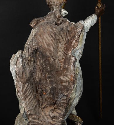 Zdjęcie nr 8: Rzeźba w całej postaci ukazuje frontalnie św. Augustyna ujętego w mocnym kontrapoście. Święty podniesioną prawą ręką trzyma pastorał, lewą zaś zdaje się odbierać rybę podawana mu przez nagie putto widniejące u jego stóp. Biskup w wysokiej infule ma pociągłą twarz o zapadniętych policzkach otoczoną rozwianą, długa brodą oraz kędzierzawymi włosami wystającymi spod złoconej infuły. Jego twarz charakteryzuje wydatny nos i usta. Ubrany jest w rozwianą mocno drapowaną sutannę, komżę obszytą u spodu frędzlą oraz kapę spiętą pod szyją. Spod sutanny widoczny jest stopa obuta w trzewik. Nagie putto u stóp biskua zostało ukazane w kontrapoście w trzech czwartych w prawo. Obiema rękami podaje świętemu rybę. Fragment jego biodra zasłani rozwiana tkanina. Putto wraz z biskupem stoją na fragmencie brzegu. 