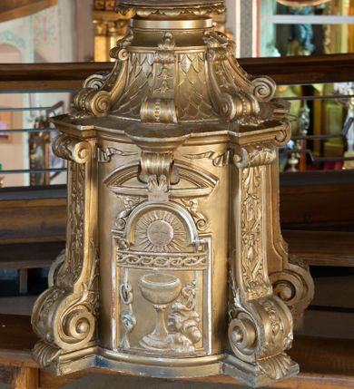 Zdjęcie nr 1: Tabernakulum w formie drewnianej, prostopadłościennej skrzynki, o wypukłym licu, na niskim, profilowanym cokole, ujętej w czterech narożach pilastrami o trzonach przechodzących w spływy wolutowe dekorowane kampanulami i ornamentem z tkaniny oraz muszlami. Pilastry dźwigają profilowany gzyms opasujący tabernakulum. Drzwiczki w formie stojącego prostokąta zamkniętego łukiem półkolistym nadwieszonym, w profilowanej ramie z płaskorzeźbionym przedstawieniem kielicha z unoszącą się nad nim hostią w glorii, z powrozem, motywem korony cierniowej oraz skałą z monogramem IHS. Nad drzwiczkami przyczółek, przerwany pośrodku konsolą podtrzymującą gzyms z wolutami i wstęgą w przyłuczach drzwiczek. Tron wystawienia w formie cokołu zwężającego się ku górze ujętego pięcioma spływami wolutowymi dekorowanymi kampanulami i perełkowaniem, pokryty rzeźbioną łuską; zwieńczony profilowaniem oraz szerszą podstawą dekorowaną ornamentem roślinnym. Struktura w całości złocona.