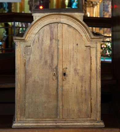 Zdjęcie nr 3: Tabernakulum w formie drewnianej, prostopadłościennej skrzynki, o wypukłym licu, na niskim, profilowanym cokole, ujętej w czterech narożach pilastrami o trzonach przechodzących w spływy wolutowe dekorowane kampanulami i ornamentem z tkaniny oraz muszlami. Pilastry dźwigają profilowany gzyms opasujący tabernakulum. Drzwiczki w formie stojącego prostokąta zamkniętego łukiem półkolistym nadwieszonym, w profilowanej ramie z płaskorzeźbionym przedstawieniem kielicha z unoszącą się nad nim hostią w glorii, z powrozem, motywem korony cierniowej oraz skałą z monogramem IHS. Nad drzwiczkami przyczółek, przerwany pośrodku konsolą podtrzymującą gzyms z wolutami i wstęgą w przyłuczach drzwiczek. Tron wystawienia w formie cokołu zwężającego się ku górze ujętego pięcioma spływami wolutowymi dekorowanymi kampanulami i perełkowaniem, pokryty rzeźbioną łuską; zwieńczony profilowaniem oraz szerszą podstawą dekorowaną ornamentem roślinnym. Struktura w całości złocona.