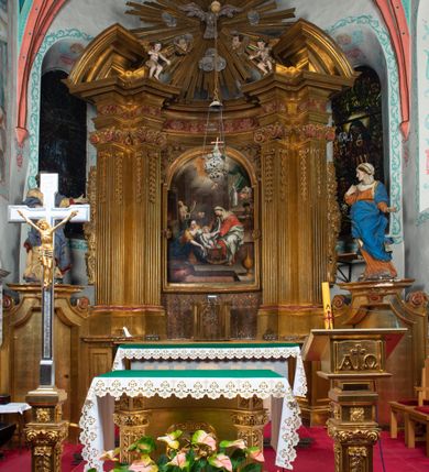 Zdjęcie nr 22: Nastawa architektoniczna, jednokondygnacyjna z glorią, jednoosiowa z bramkami, ustawiona na dwustrefowym cokole, na planie półowalu. Ołtarz kamienny, prostopadłościenny, z wcięciami na bocznych ściankach, zakończony profilowanym gzymsem; mensa kamienna. Na ściance frontowej namalowana scena Ostatniej Wieczerzy. Na ołtarzu ustawione drewniane tabernakulum obite blachą, w formie prostopadłościanu o wypukłych bokach, w narożach ujętego pilastrami o kanelowanych trzonach, dźwigającymi profilowany gzyms. Drzwiczki dwuskrzydłowe, w formie stojącego prostokąta zamkniętego łukiem półkolistym nadwieszonym, ujęty ramą z przedstawieniem baranka stojącego na ołtarzu, z którego piersi wypływa krew do kielicha; w górnej części monogram IHS. Nastawa ujęta dwiema parami filarów ustawionych pod kątem, o kanelowanych trzonach, dekorowanych kampanulami, podtrzymujących pełne belkowanie wyłamane na ich osi, z silnie wysuniętym gzymsem. Fryz zdobiony ornamentem roślinnym, w jego centrum kartusz z napisem „SANCTVS”. Na belkowaniu fragmenty zdwojonego, półkolistego przyczółka, z siedzącymi puttami. Pole główne wypełnione wnęką w formie stojącego prostokąta zamkniętego łukiem półkolistym nadwieszonym, ujęta profilowaną ramą, z obrazem Narodzenia Najświętszej Marii Panny. W przyłuczach dekoracja roślinna. Nastawa flankowana uszami utworzonymi z karbowanej wstęgi i ornamentu roślinnego. W miejscu zwieńczenia gołębica Ducha Świętego w otoku z obłoków i uskrzydlonych główek anielskich, w glorii promienistej. Bramki z drzwiczkami w formie stojącego prostokąta o wklęsłych górnych narożach ze ślimacznicami, ujęte grubą opaską, zwieńczone kluczem z herbem Uniwersytetu Jagiellońskiego oraz fragmentem profilowanego gzymsu, który stanowi podstawę dla figur św. Anny i św. Joachima. Herb lewej bramki z syglami „M[atthaeus] F[ranciscus]  K[alewski] / D[ecanus] S[antae] A[nnae] / C[uratus] Z[elenensis]”, herb prawej bramki z inskrypcją „A[NNO] D[OMINI] / 17/28”. Struktura w całości złocona, detale glorii srebrzone. Na odwrocie nastawy inskrypcja: „ODNOWIONO OŁTARZ ZA STARANIEM / KS(IĘDZA) JANA MICHALIKA. R(OKU) 1902.”